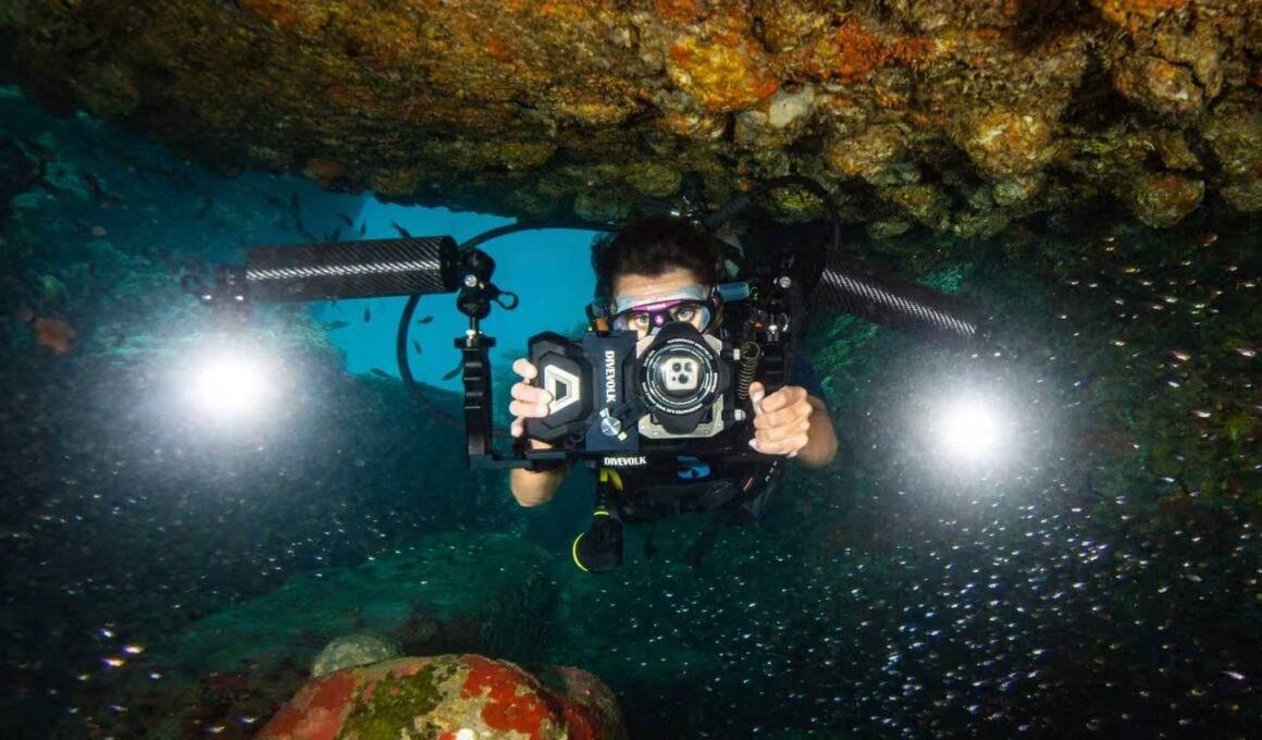 A diver holding a smartphone in a DiveVolk SeaTouch underwater housing on a coral reef