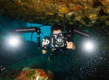 A diver holding a smartphone in a DiveVolk SeaTouch underwater housing on a coral reef
